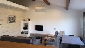A modern living room with a sofa, a rocking chair, a TV, and a dining table.