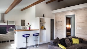 A modern kitchen with a central island, bar stools, and a dining area with a table and chairs.