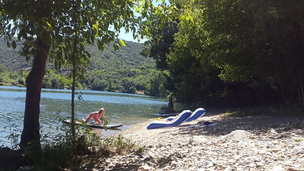 A lakeside setting with a boat and lounge chairs on the shore.