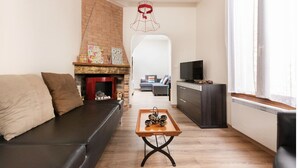 A living room with a fireplace, a sofa, a coffee table, and a TV. - House borders of Marne, between Disney and Paris! (Le Perreux-Sur-Marne)