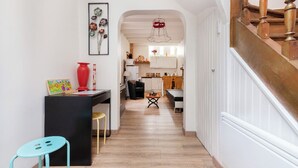 A narrow hallway with a staircase on the right, leading to a dining area with a wooden table and chairs. - House borders of Marne, between Disney and Paris! (Le Perreux-Sur-Marne)