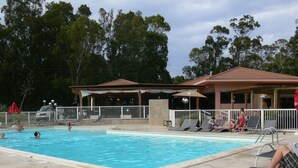 A swimming pool with lounge chairs and a covered seating area.