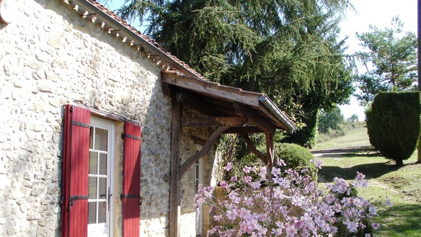 A stone building with red shutters and a wooden porch.