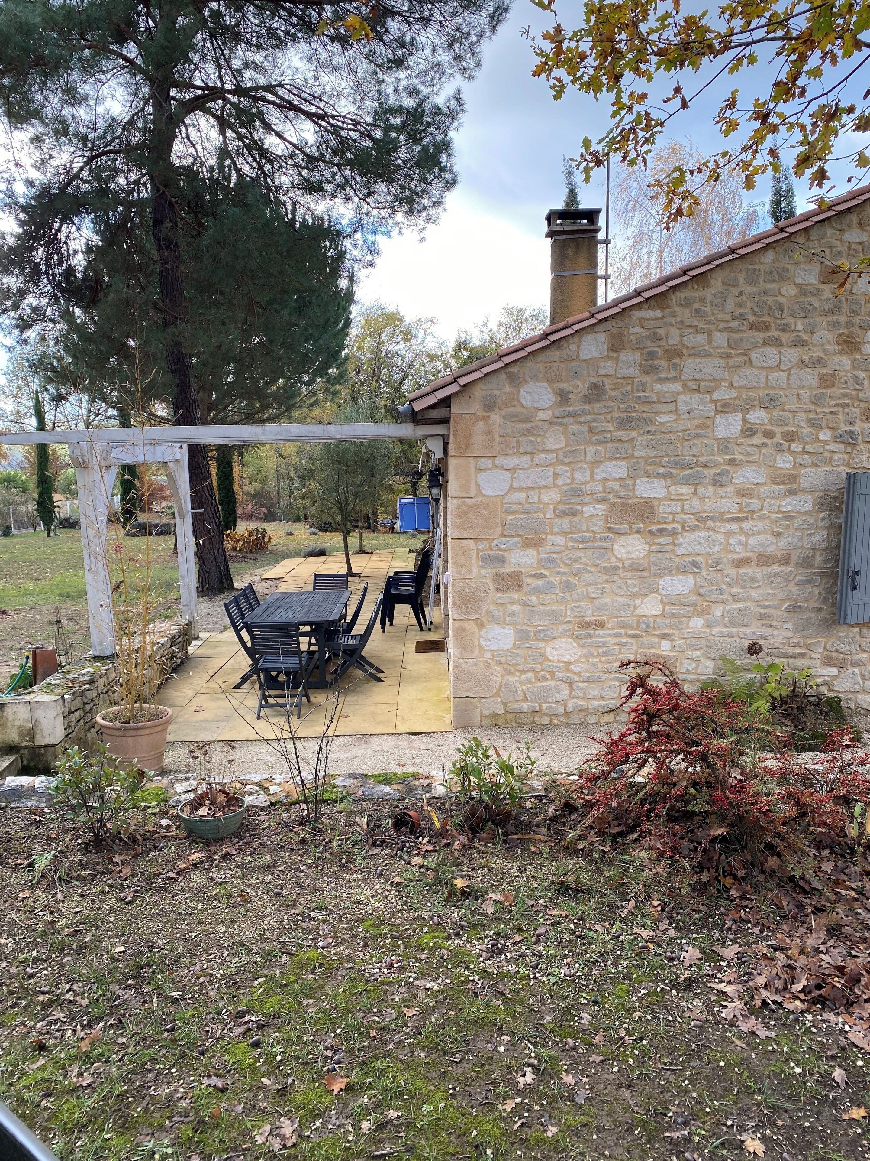 Ein Steinhaus mit einer Terrasse, die einen Tisch und Stühle bietet.