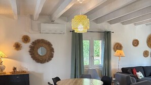 Een moderne woonkamer met een ronde houten tafel, zwarte stoelen, een grijze bank en decoratieve wandkunst.