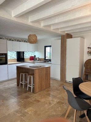 A modern kitchen with white cabinets, a wooden island, and a dining area with a table and chairs.