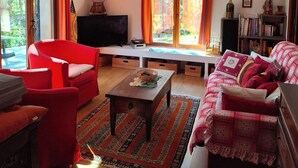 A living room with a red sofa, a wooden coffee table, a TV, and a bookshelf. - Beau Mazet 75m2, large garden in pine forest, Private domain with Swimming pool, Tennis .. (Sainte-Maxime)