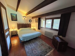 A bedroom with a bed, bedside lamps, a rug, a clock, and a window.