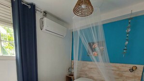 Een slaapkamer met een bed, een nachtkastje, een wandairconditioner en een raam met gordijnen.
