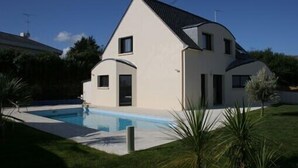 Et moderne hus med to etager og en swimmingpool i baghaven.