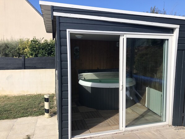 Un jacuzzi en un espacio exterior moderno con puerta corredera de vidrio.