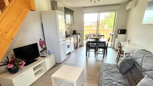 A modern living room with a sofa, a TV, a coffee table, and a kitchen area with a washing machine. - T2 apartment, 40 m2 350m from Lecques beach, quiet. Air conditioning. Private parking (Saint Cyr sur Mer)