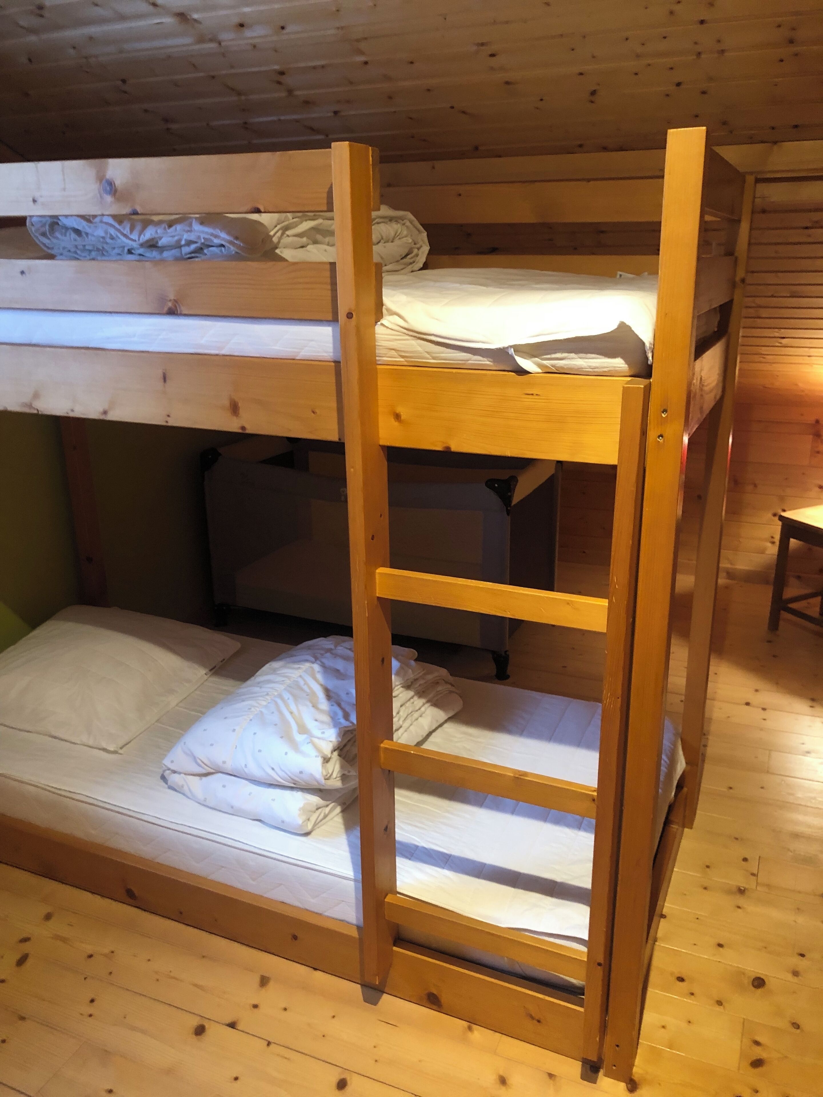 Un lit superposé avec une échelle, des murs en bois et une petite table.