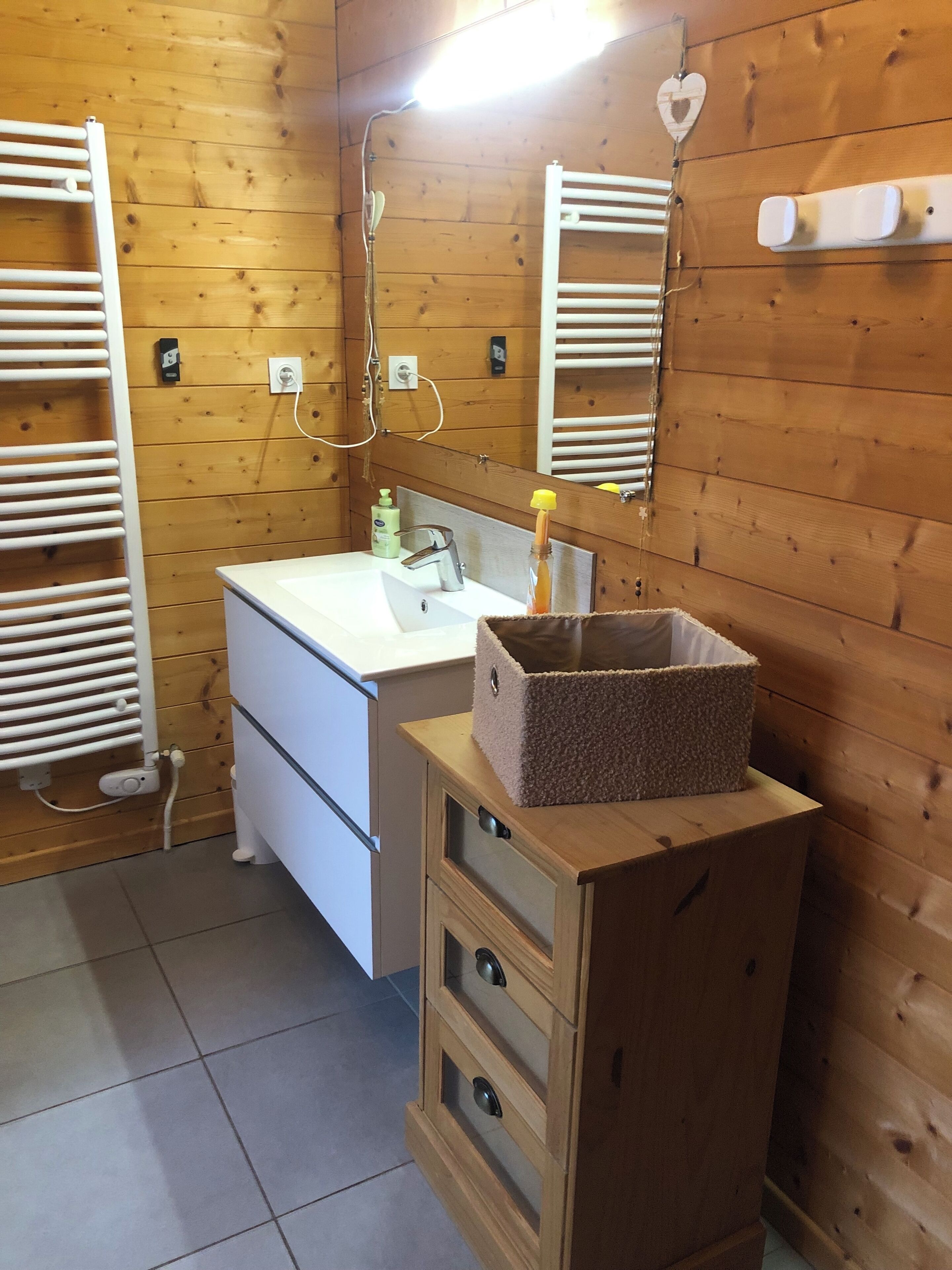 A bathroom with wooden panel walls, a white sink, a mirror, and a towel rack.