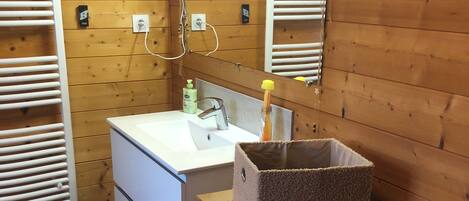 A bathroom with wooden panel walls, a white sink, a mirror, and a towel rack.
