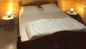 Een slaapkamer met houten lambrisering, een bed, twee nachtkastjes met lampen, en decoratieve hartvormige versieringen aan de muur.