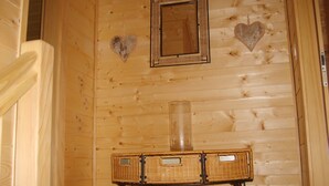 Een houten interieur met een rieten tafel, een spiegel en twee hartvormige decoraties aan de muur.