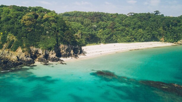 A coastal landscape with a sandy beach and clear turquoise waters.