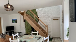 A dining area with a round table, white chairs, and a staircase with a wooden railing.