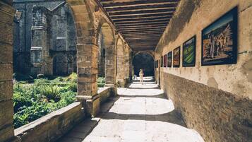 A corridor with stone walls, a wooden ceiling, and a person standing in the distance.