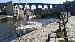 A boat docked at a riverside pier with a stone bridge in the background.
