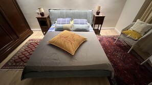 Une chambre à coucher comprenant un lit, deux tables de chevet, une chaise et un tapis à motifs.