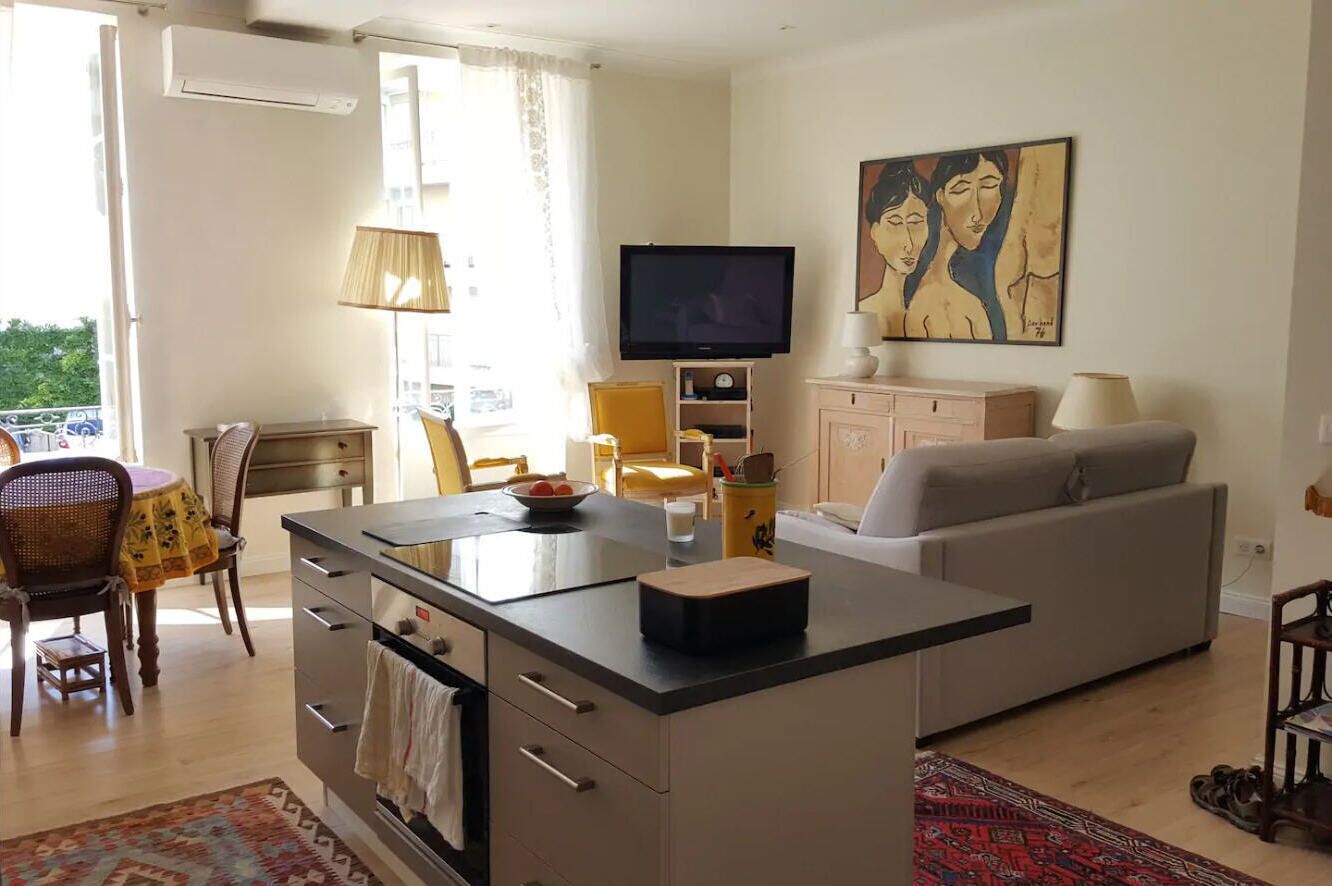 A modern living room with a sofa, a TV, and a dining area with chairs and a table.