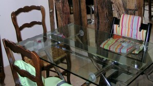 A dining area with a glass table, wooden chairs, and rustic wooden beams.