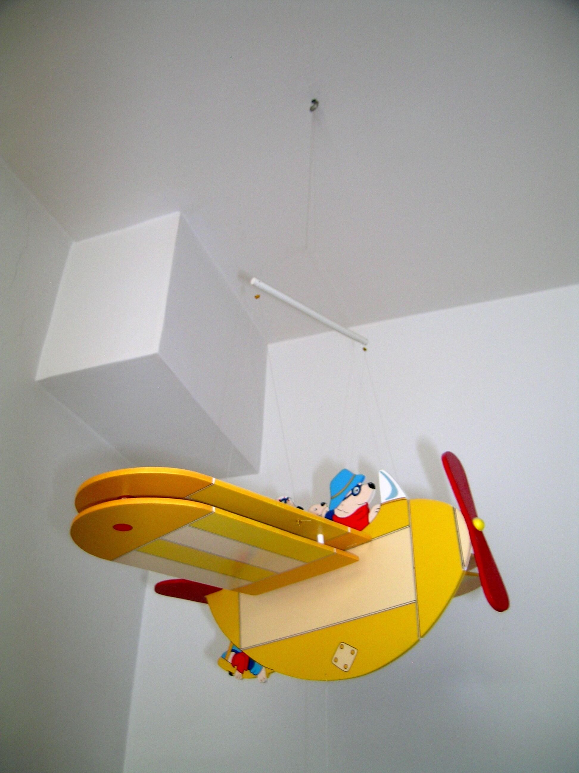 Un avión amarillo colgando del techo con un personaje encima.