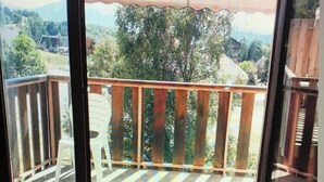 A balcony with a wooden railing and a view of a green landscape.