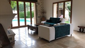 A spacious living area with a pool view, a stone wall, and a cozy seating arrangement. - Former sheepfold in an old village with garden and swimming pool (Saint-Mathieu-De-Tréviers)