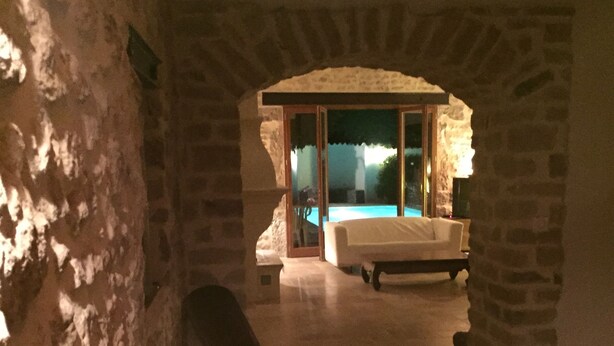 A stone-walled room with a pool area visible through a glass door. - Former sheepfold in an old village with garden and swimming pool (Saint-Mathieu-De-Tréviers)