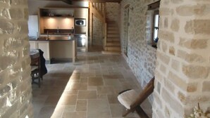 A stone-walled interior with a kitchen area, wooden beams, and a staircase. - Former sheepfold in an old village with garden and swimming pool (Saint-Mathieu-De-Tréviers)