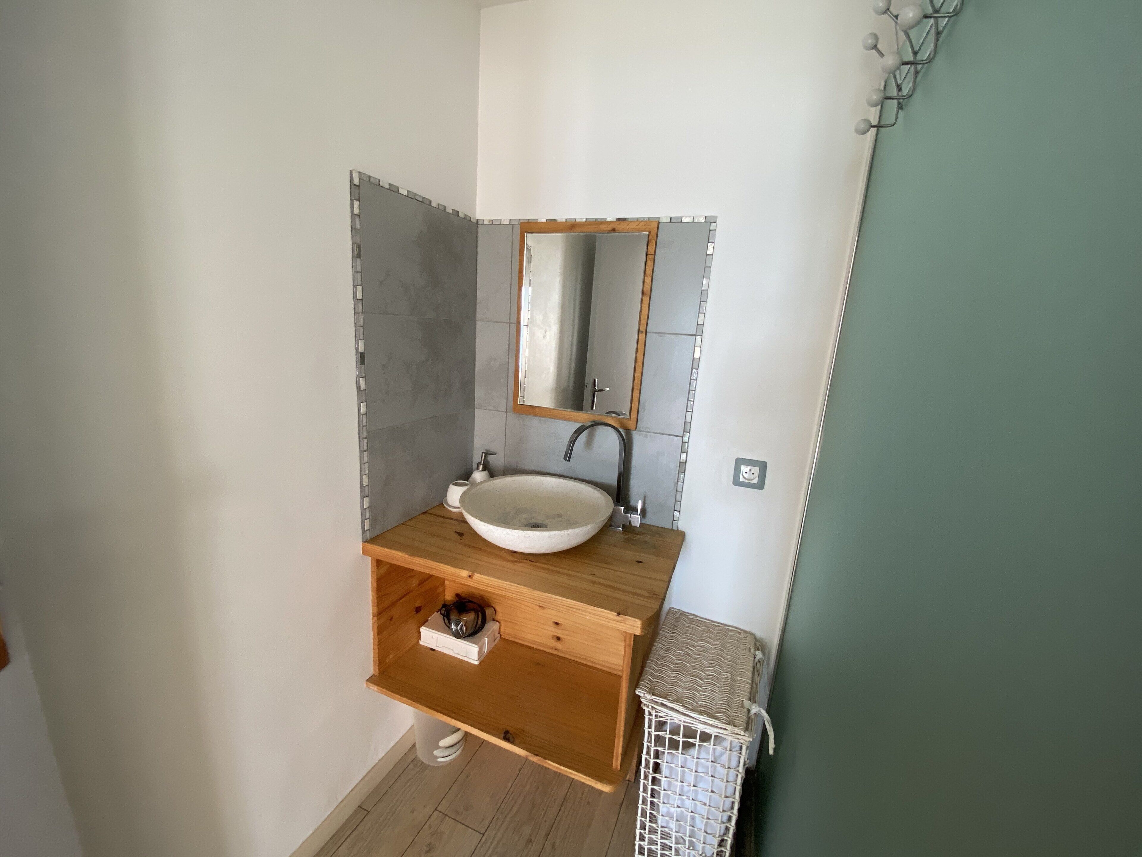 Ein Badezimmer mit einem Holzbadschlank, einem weißen Waschbecken und einem Spiegel.
