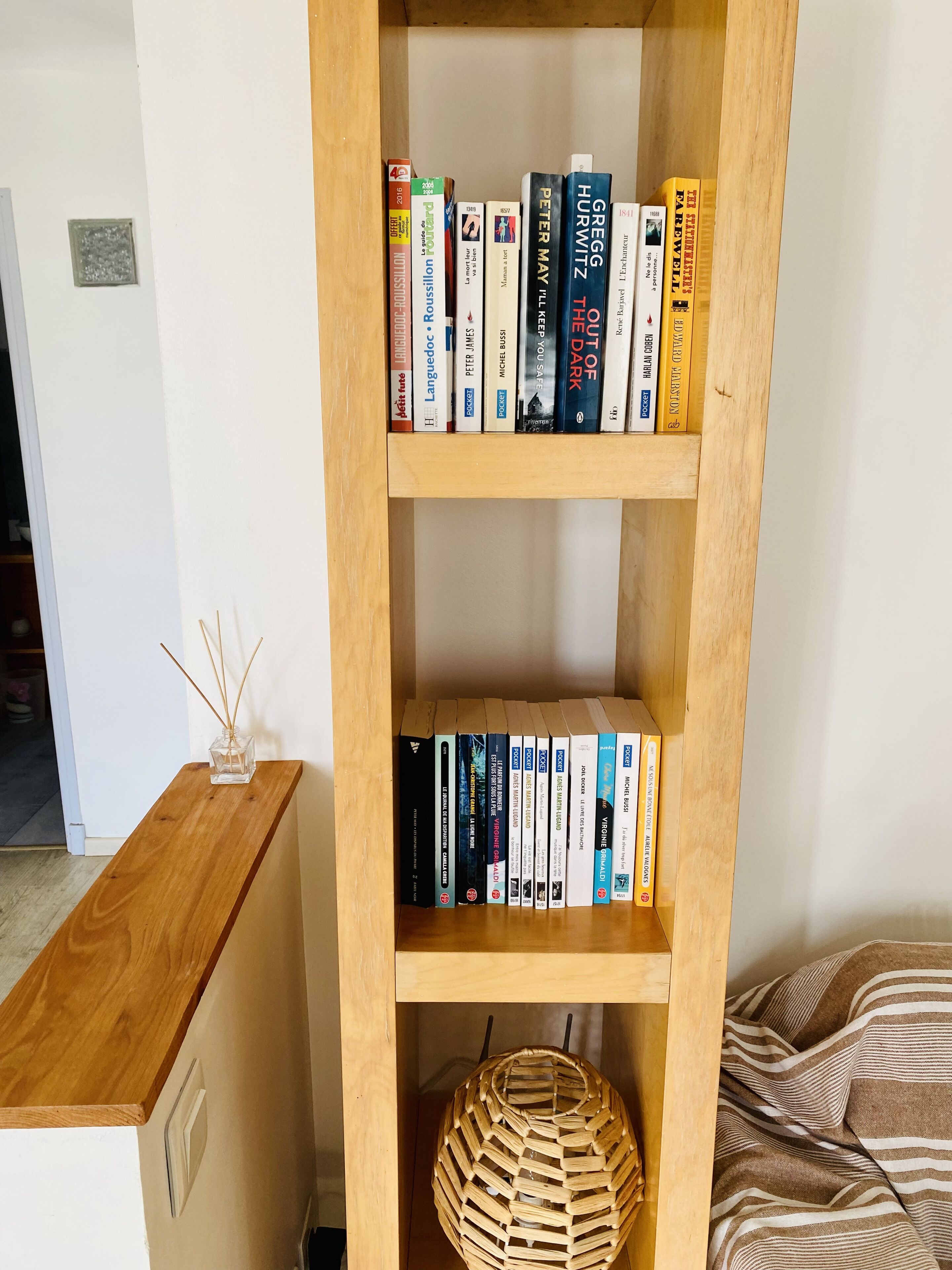 Una libreria con libri e un cesto in vimini.