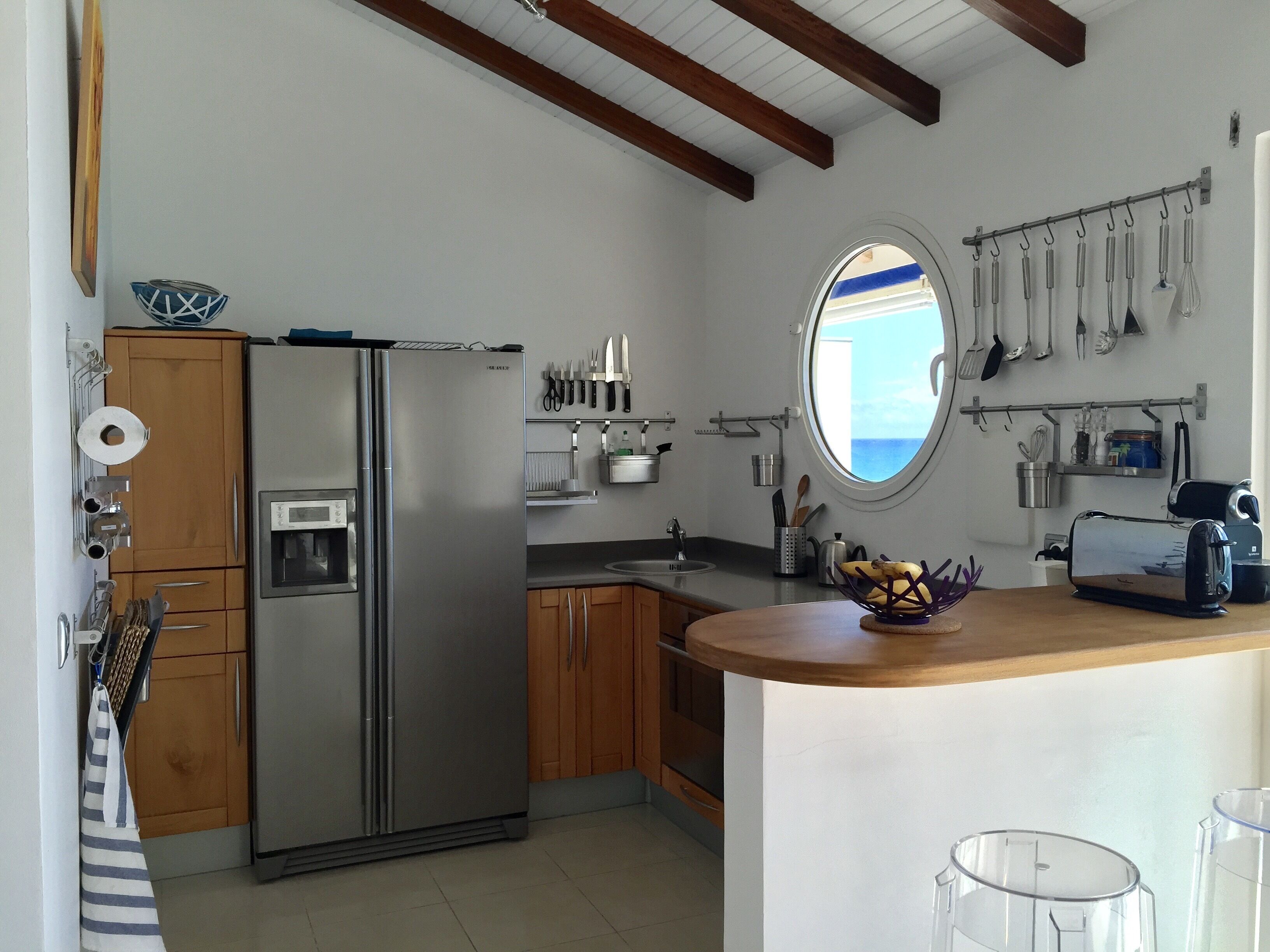 Una cucina moderna con frigorifero integrato, mobili in legno, un'isola centrale e una finestra con vista sul mare.