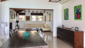 Un'ampia zona giorno con tavolo da pranzo, divano e opere d'arte alle pareti.
