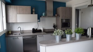 Una cocina moderna con armarios grises, lavavajillas, microondas y plantas en macetas sobre la encimera.