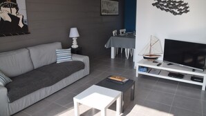 Una sala de estar moderna con sofá, mesa de centro, mueble para televisión y obras de arte en las paredes.