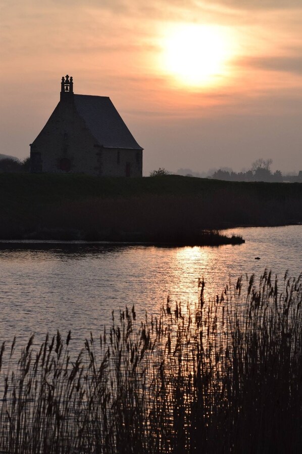 A house by a body of water during sunset.