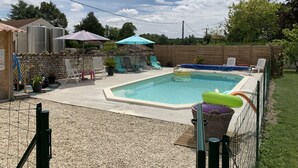 A backyard with a swimming pool, lounge chairs, and umbrellas. - Private garden, swimming pool, picturesque village location, bank, bakery (saint fort sur gironde)