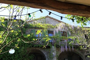 Experience a serene retreat amidst lush greenery and vibrant flowers, surrounded by a traditional stone building's rustic charm.