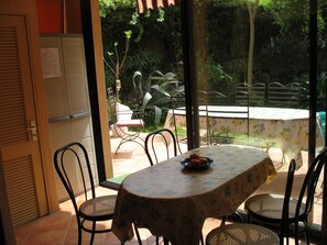 A dining area with a table covered by a floral tablecloth, surrounded by chairs.