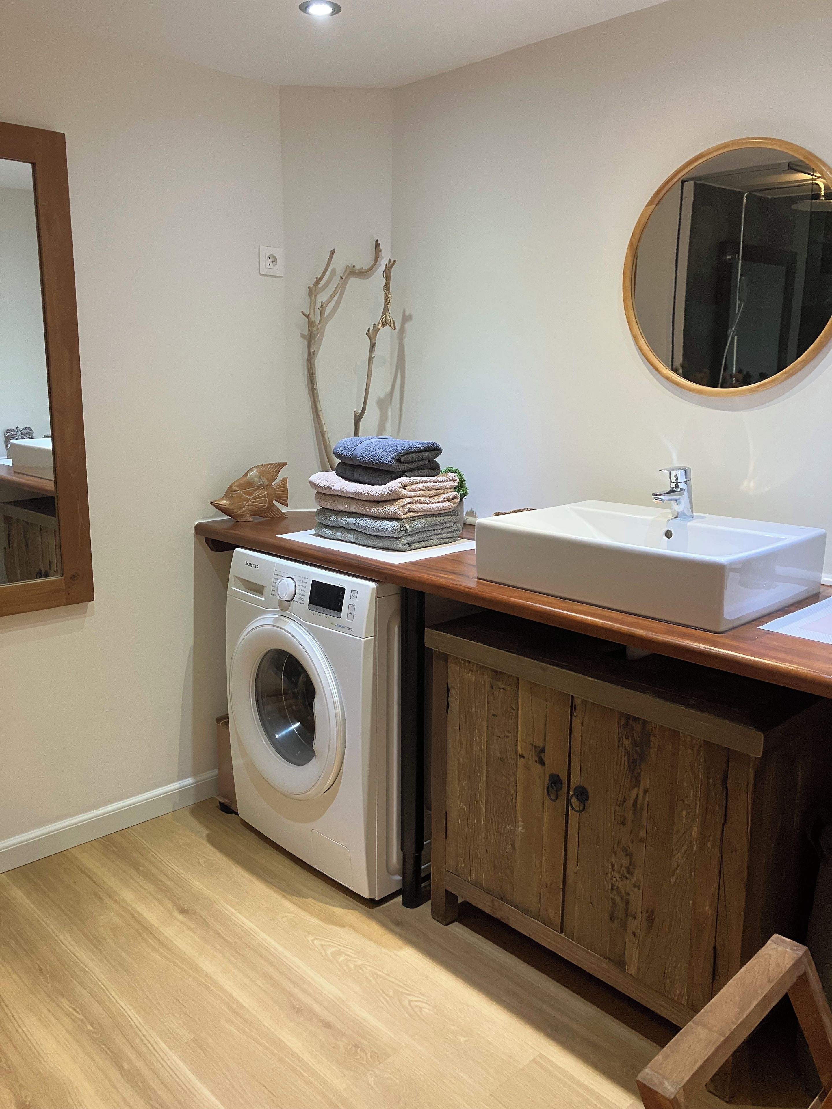 A compact laundry area with a washing machine, a sink, and a mirror.