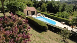 A swimming pool with a stone house, surrounded by well-maintained hedges and flowering bushes. - Quiet, dead-end street, 10 minutes' walk from the town center, ground floor (Sarlat-La-Canéda)
