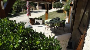 A covered patio area with a table and chairs, surrounded by greenery and a gravel path. - Quiet, dead-end street, 10 minutes' walk from the town center, ground floor (Sarlat-La-Canéda)