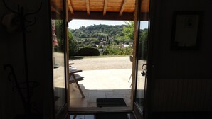 A doorway leading to an outdoor patio with a view of a village and hills. - Quiet, dead-end street, 10 minutes' walk from the town center, ground floor (Sarlat-La-Canéda)