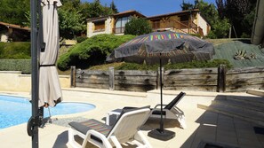 A poolside area with lounge chairs, a covered umbrella, and a wooden fence. - Quiet, dead-end street, 10 minutes' walk from the town center, ground floor (Sarlat-La-Canéda)