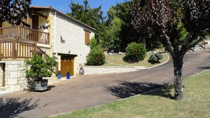 A stone building with a wooden balcony, a wooden door, and potted plants. - Quiet, dead-end street, 10 minutes' walk from the town center, ground floor (Sarlat-La-Canéda)