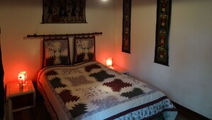 Une chambre à coucher comprenant un lit, une table de chevet, une lampe fixée au mur et des éléments décoratifs suspendus au mur.
